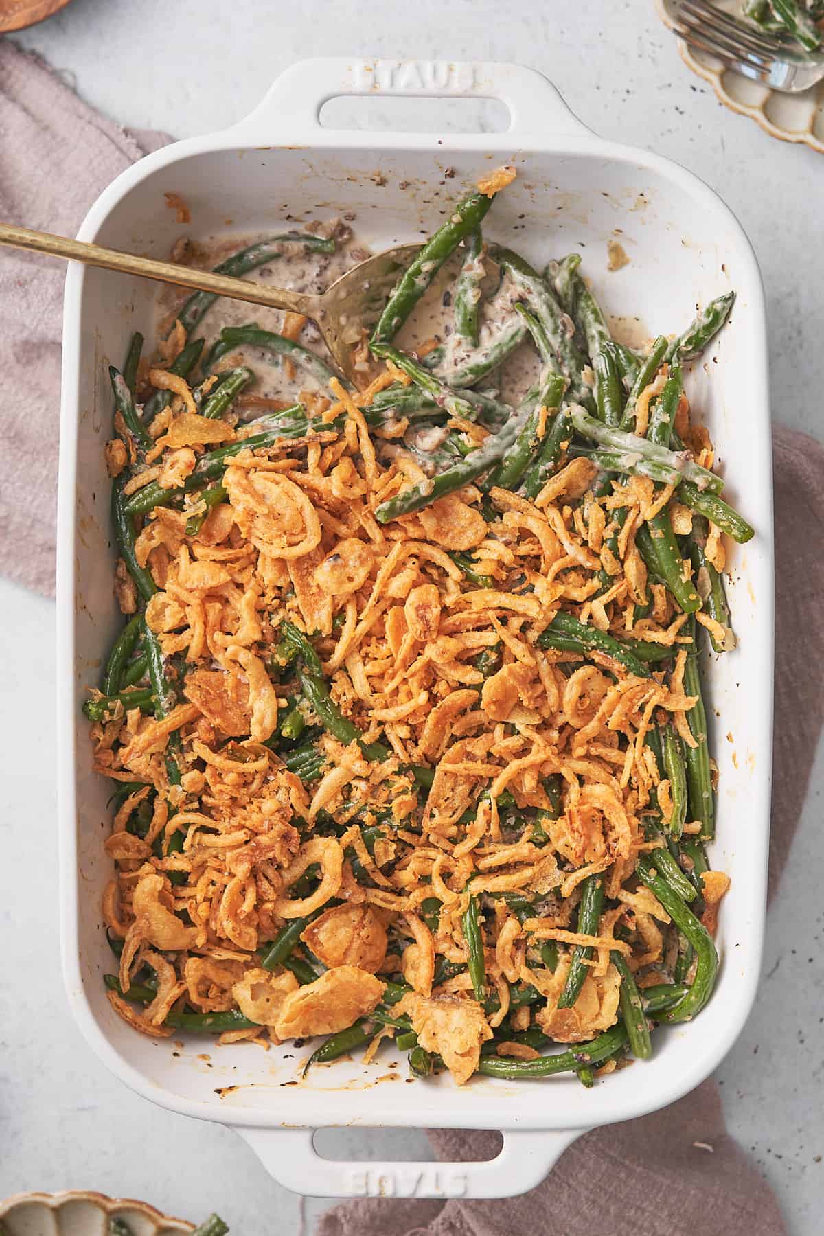 delicious keto green bean casserole with a large spoon in the dish, with crispy fried onions. 