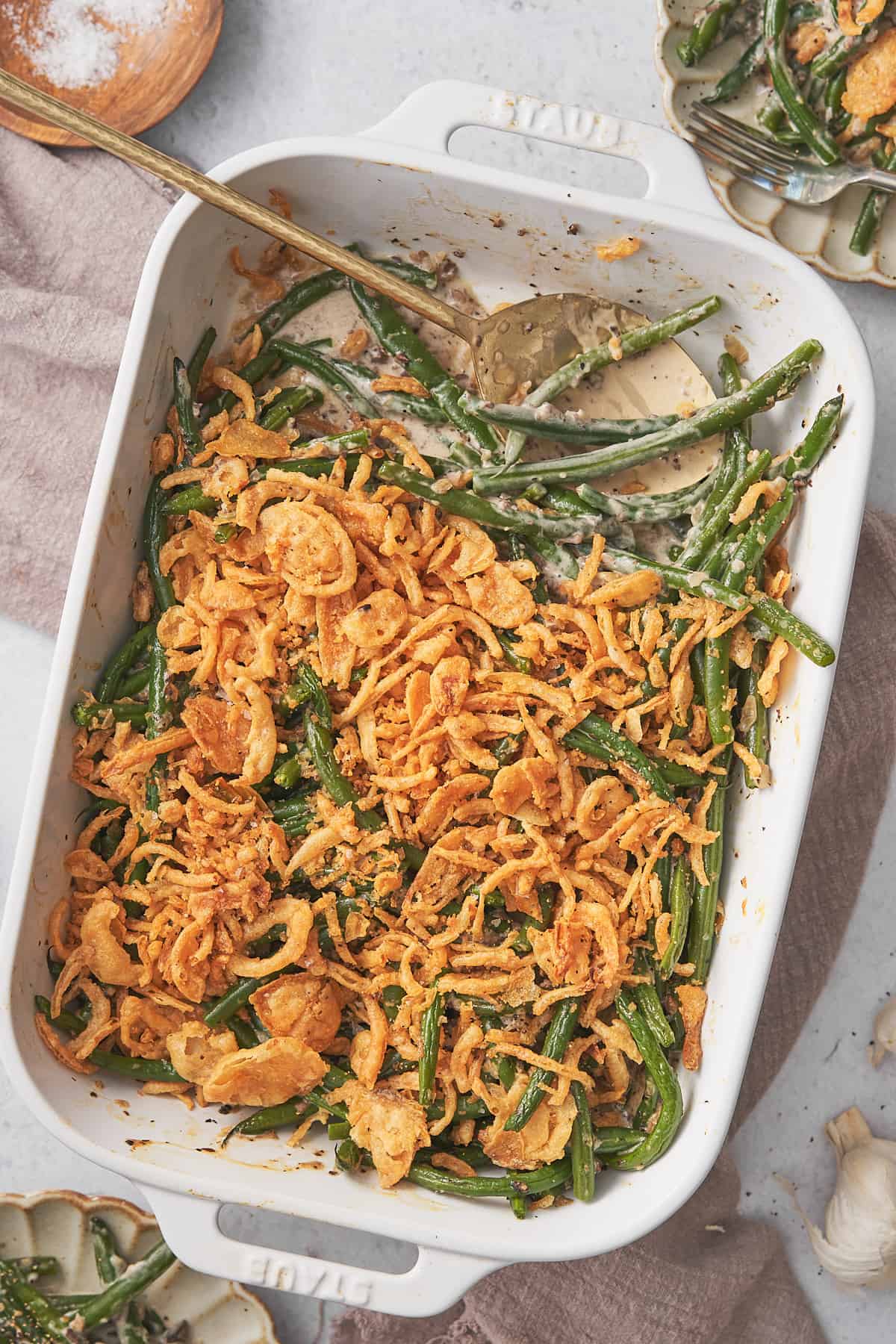 keto green bean casserole in a white rectangular casserole dish with a spoon in the dish. 