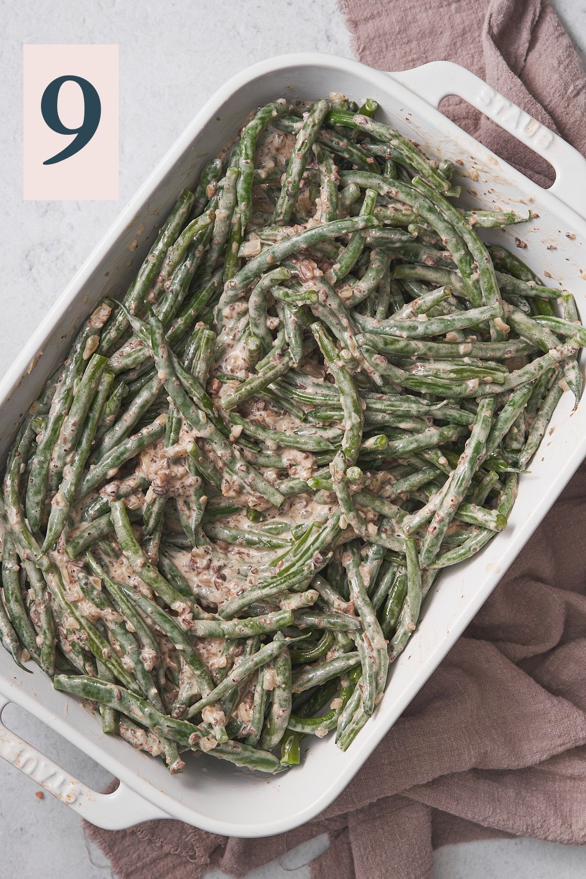 green beans tossed in a creamy mushroom soup mixture in a white rectangular casserole dish. 