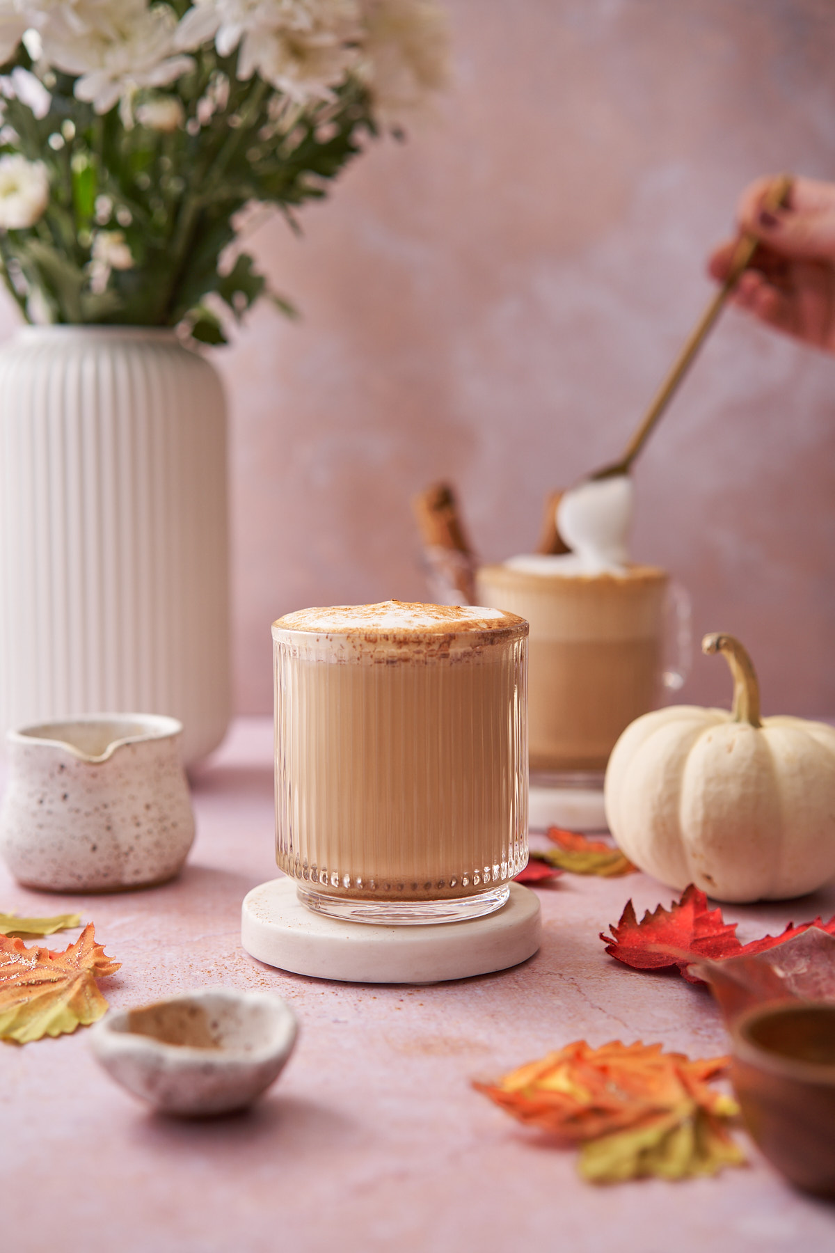 hand scooping frothed milk onto the top of a maple latte. 