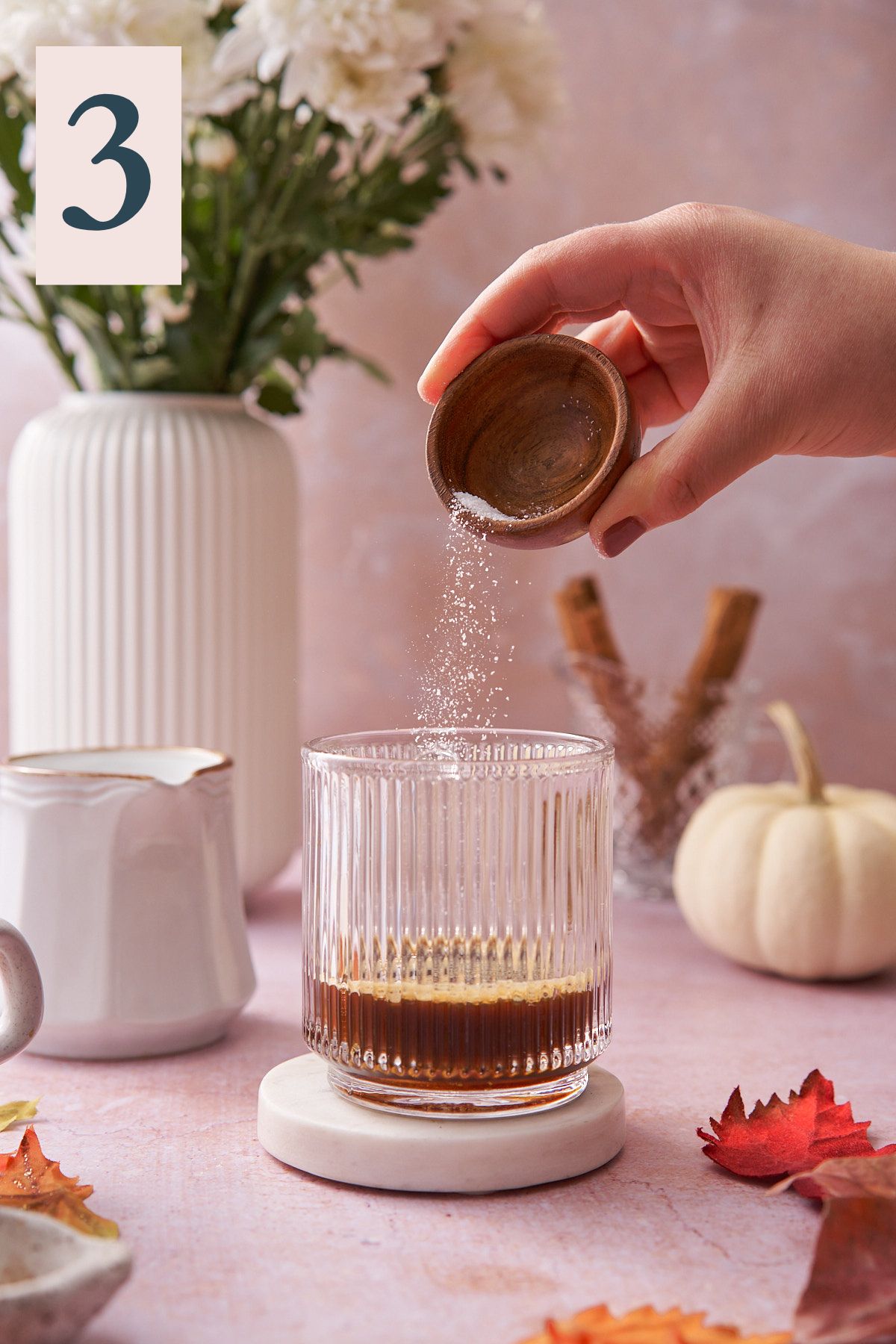 hand shaking kosher salt into a glass mug. 