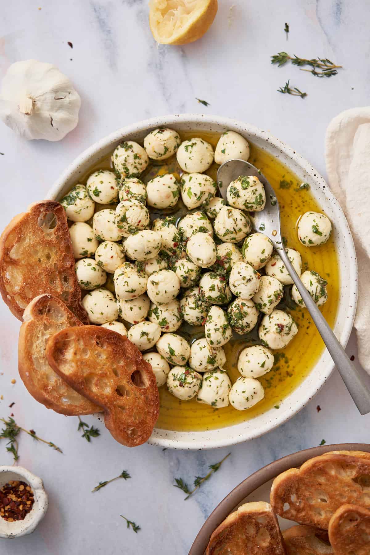 marinated mozzarella on a rimmed plate with crispy crostini. 