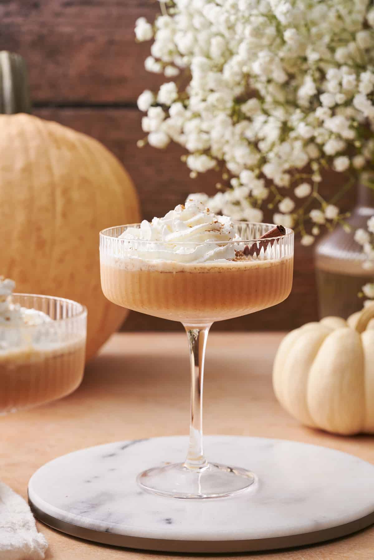 pumpkin martini recipe with pumpkins and white flowers in the background. 