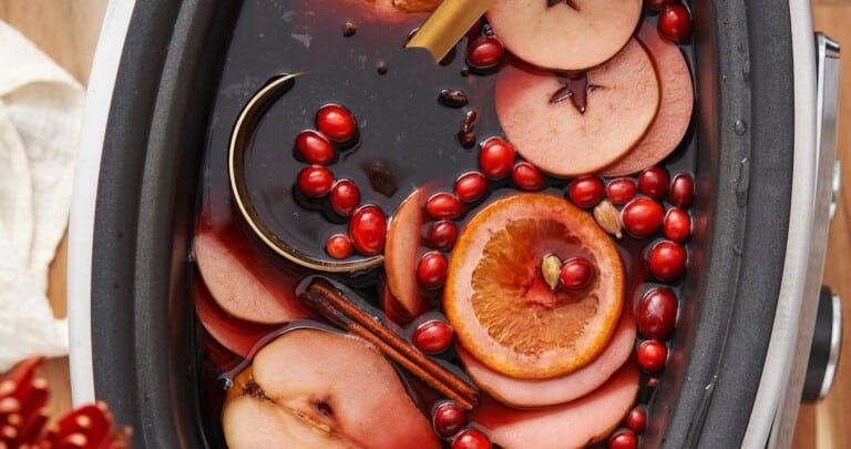 slow cooker mulled wine with a gold metal ladle.
