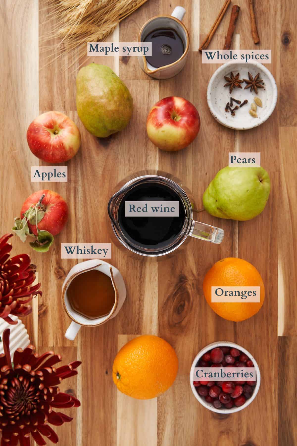 ingredients to make slow cooker mulled wine laid out in ceramic bowls and labeled to denote each ingredient. 