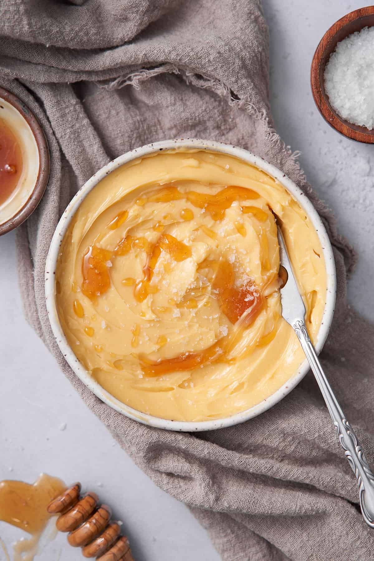 whipped honey butter in a small white ceramic bowl, topped with fresh honey and sea salt flakes. 