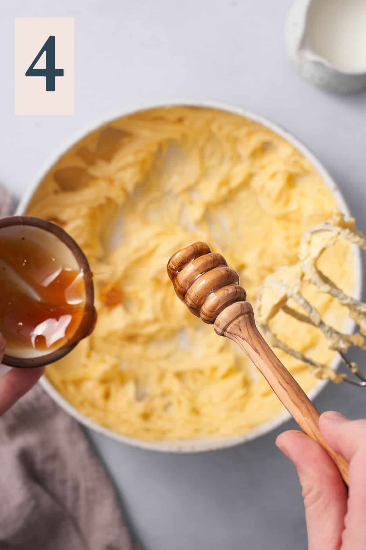 hand adding honey to whipped butter in a mixing bowl with a honey dripper. 