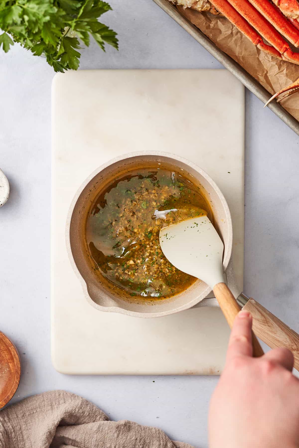 Hand making lemon butter garlic sauce in a small saucepan and stirring with a rubber spatula.