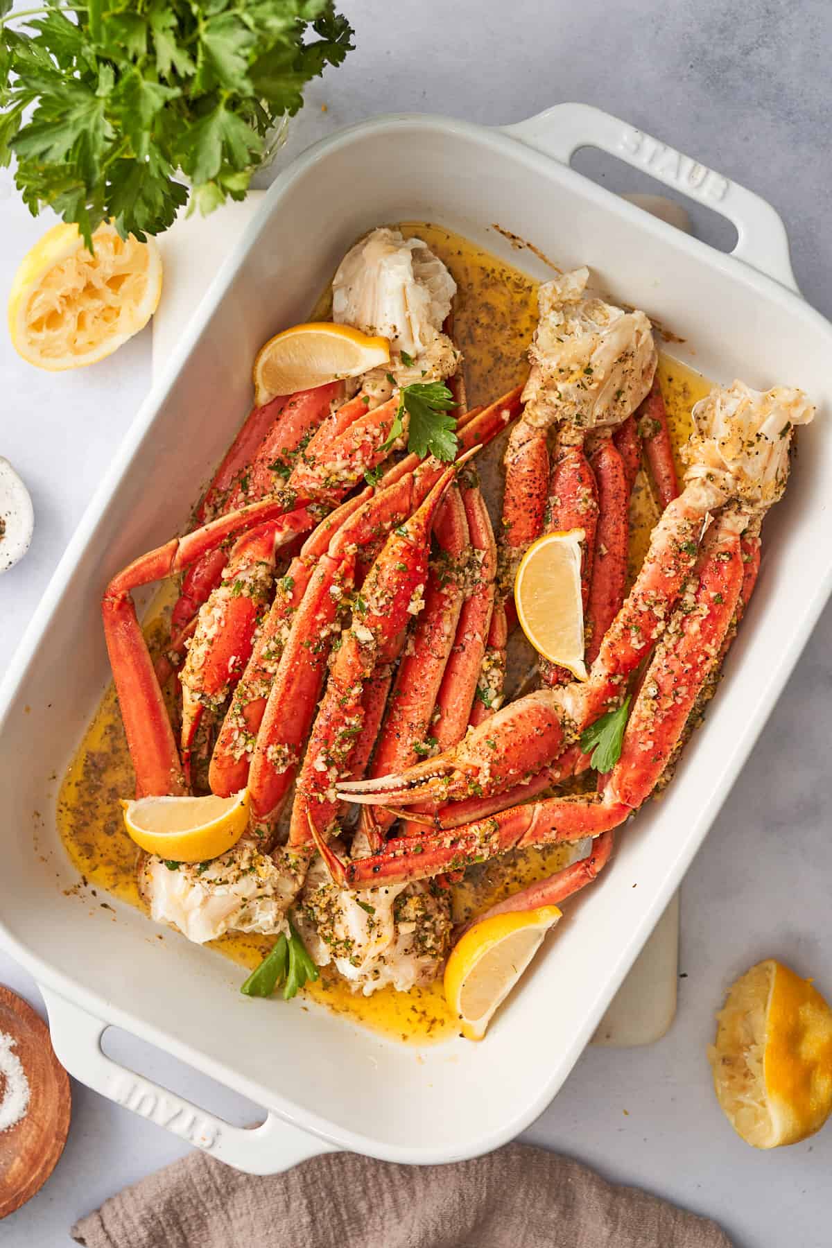 Baked crab legs with garlic butter and lemon sauce in a casserole dish.