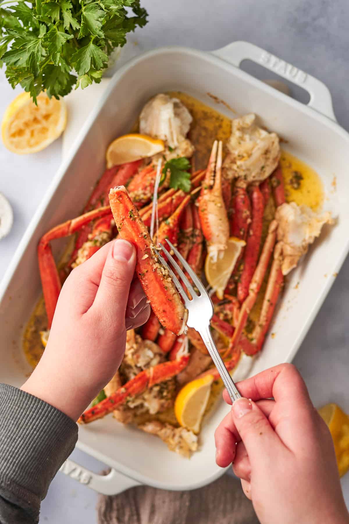 Hands inserting a fork inside a crab leg to remove the meat.