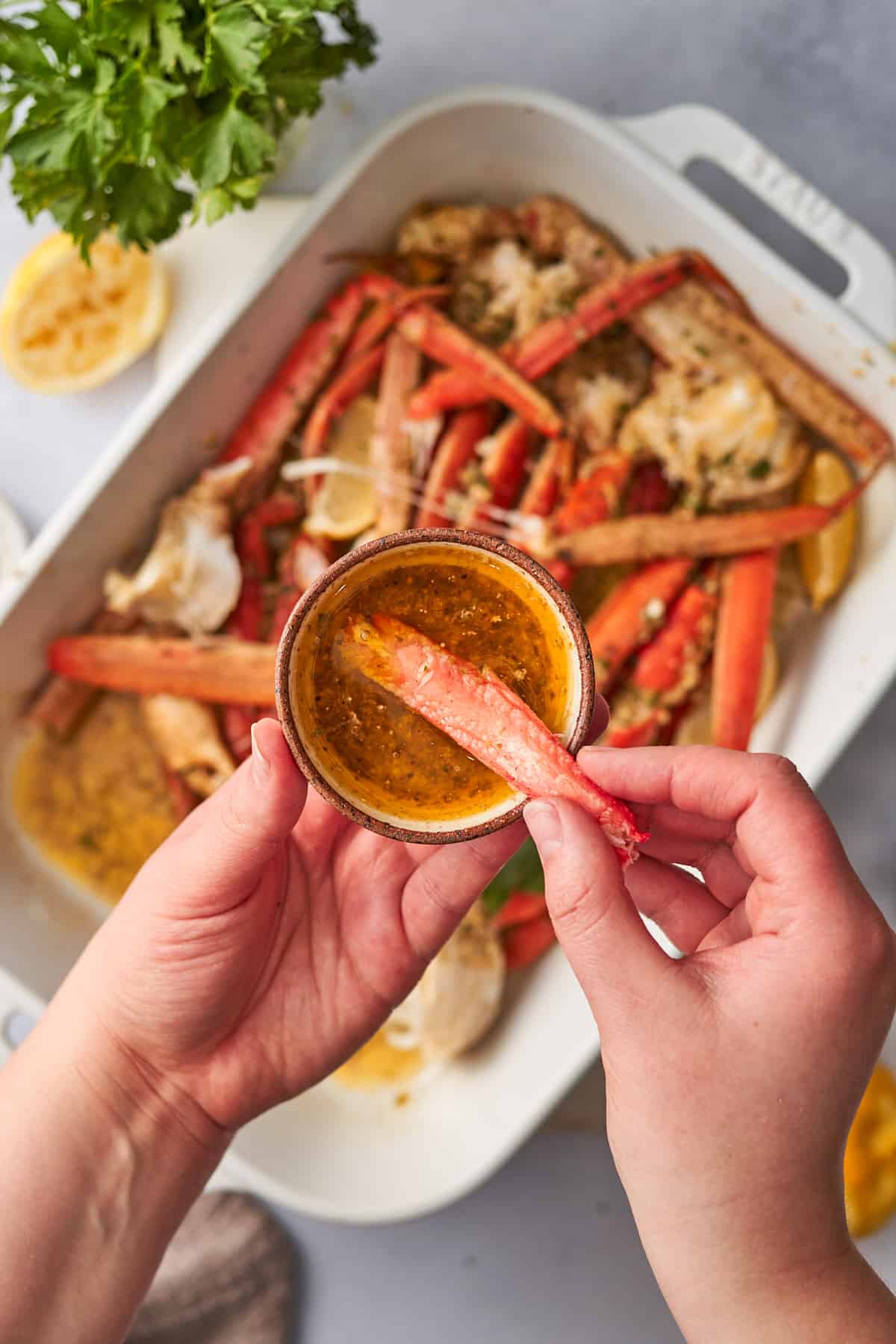 Hand dipping crab meat into a spicy garlic butter sauce.