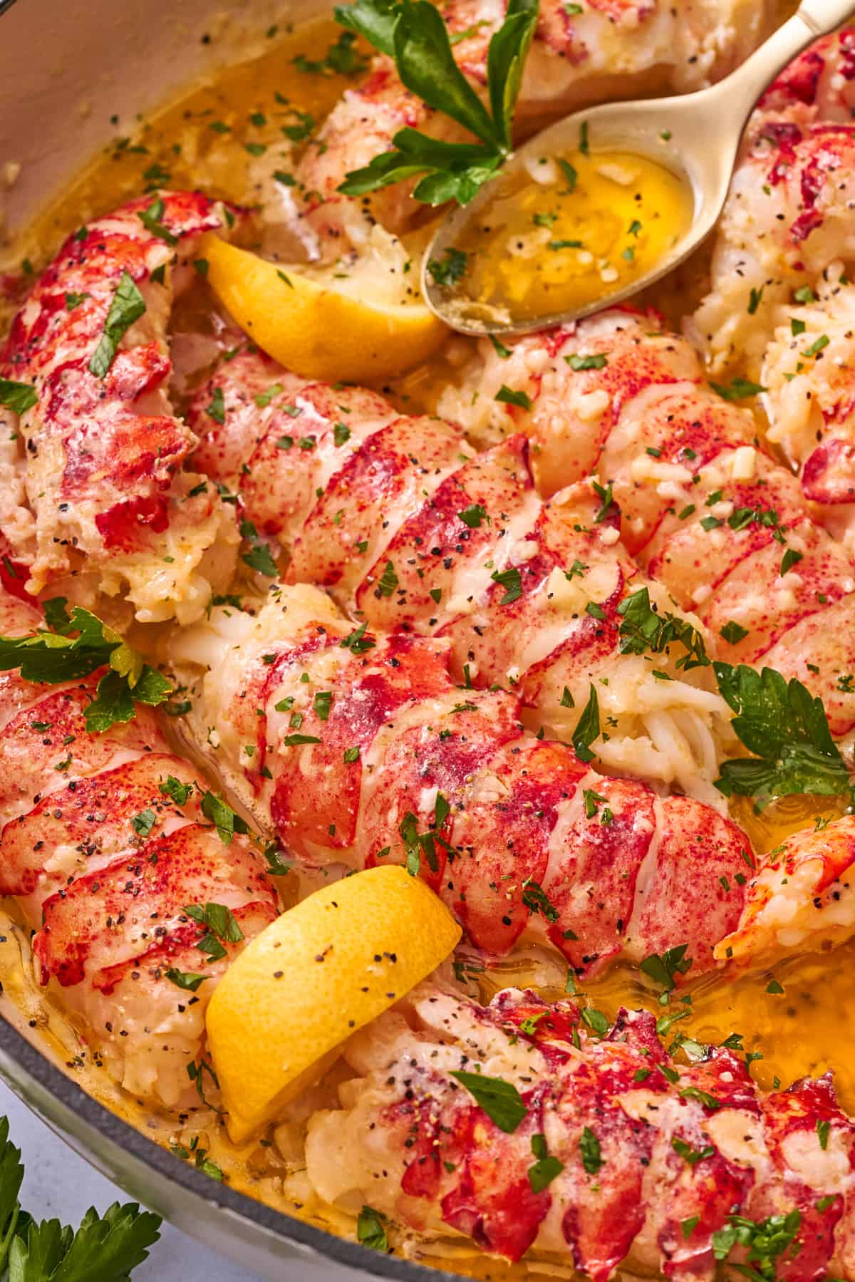 close up macro shot of butter poached lobster tails with lemons and parsley. 