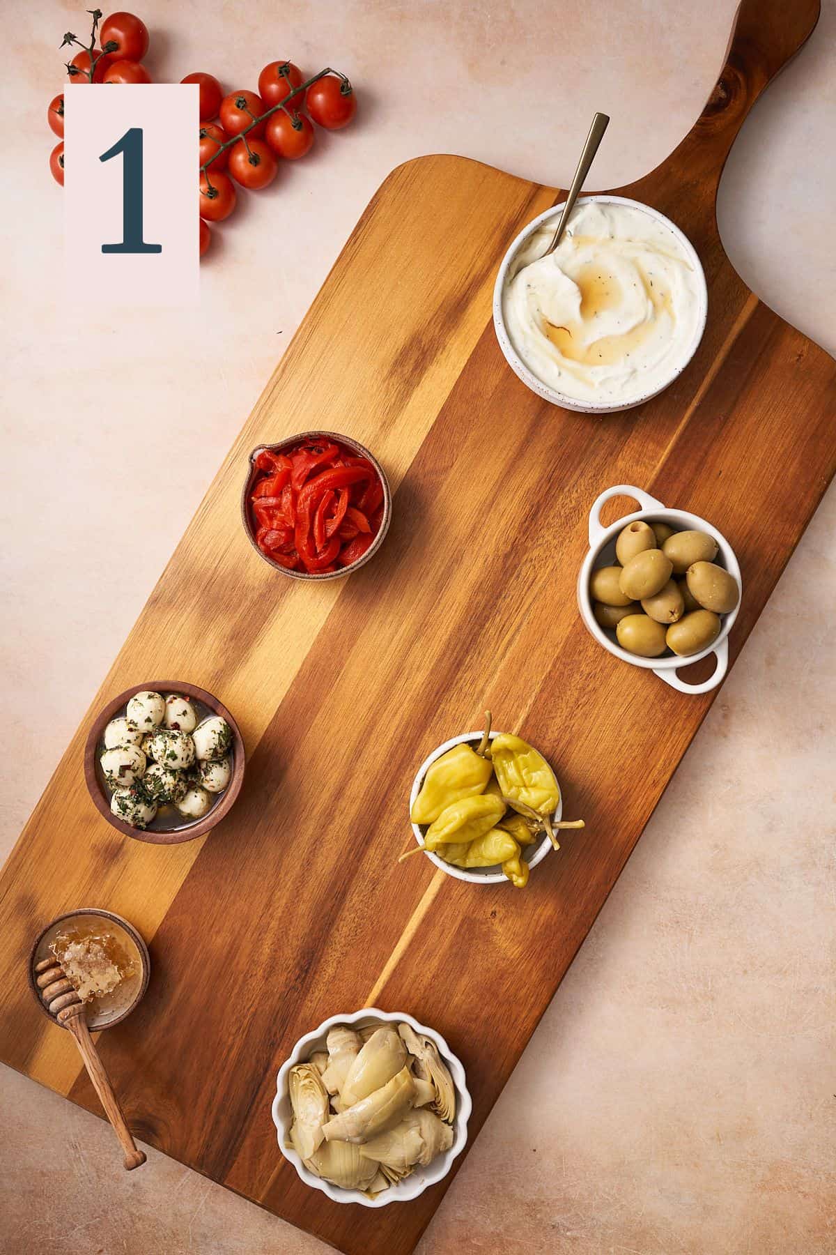 wooden board with a few small bowls of dips, spreads, olives, and whipped ricotta. 