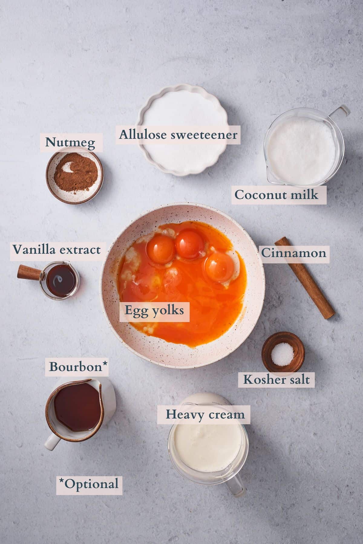 ingredients to make keto eggnog laid out in small bowls and labeled to denote each ingredient.