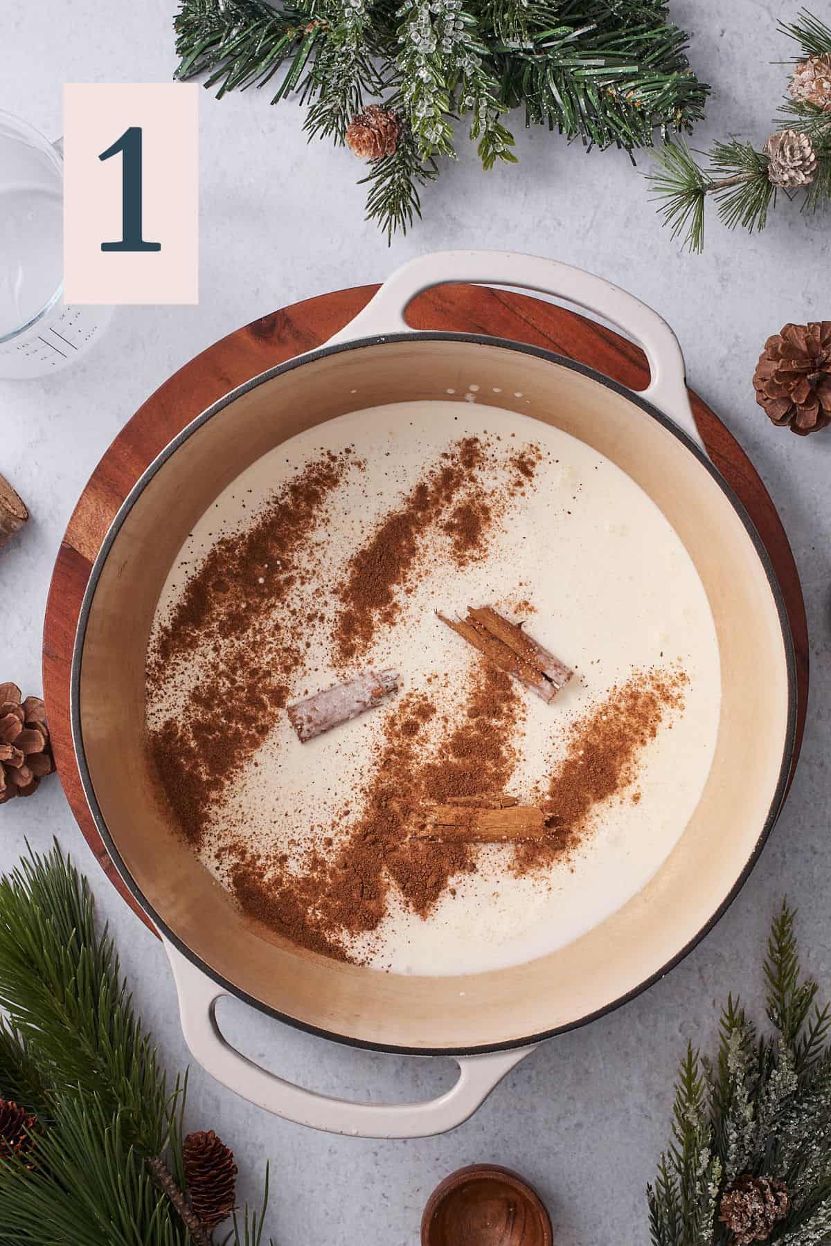 enameled dutch oven with cream, nutmeg, and cinnamon sticks in it. 