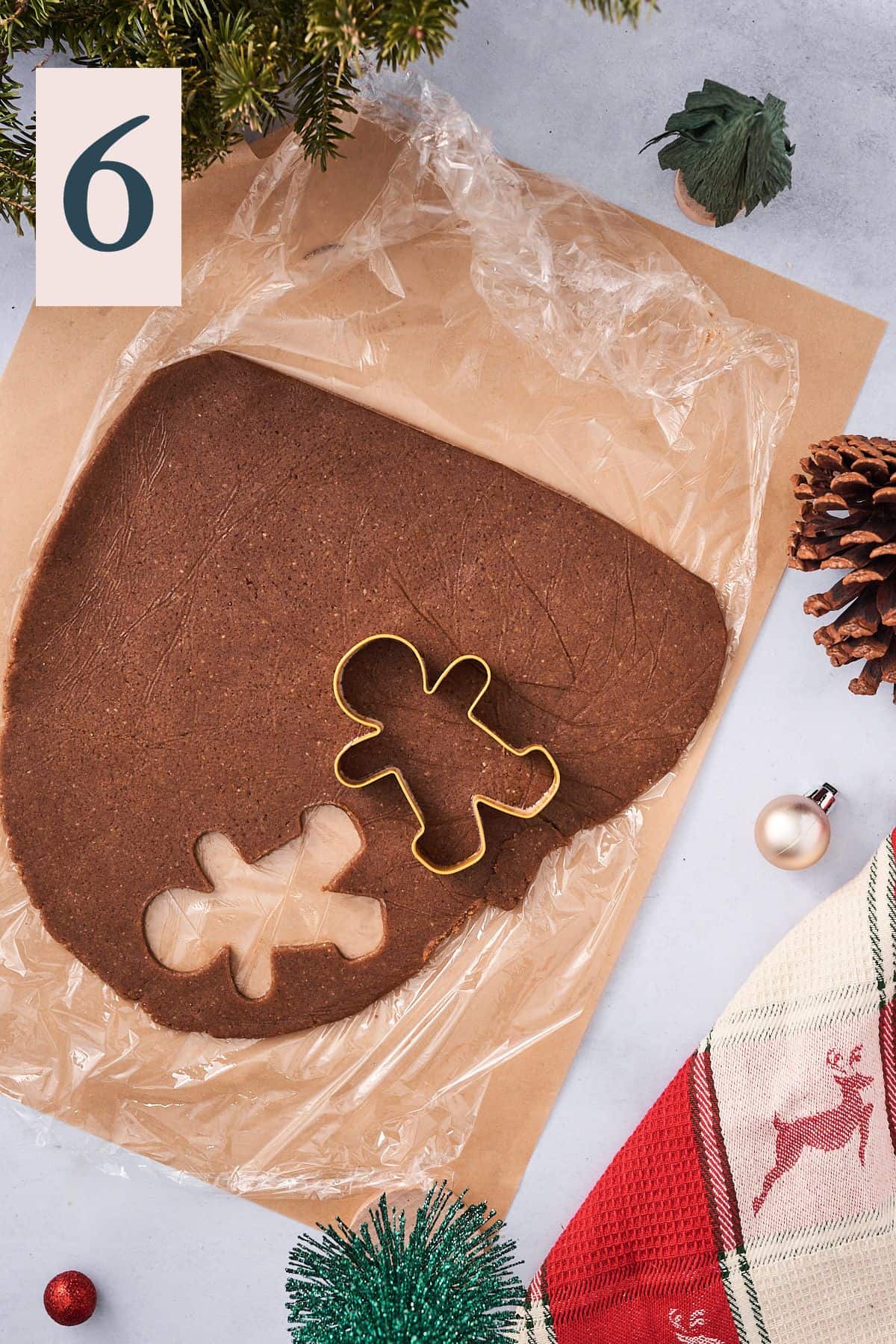 gingerbread cookie dough being cut into shapes on parchment paper.