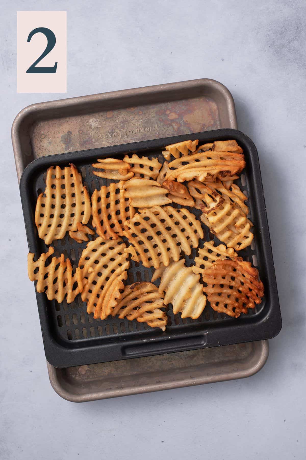 waffle fries on tray on top of baking sheet.