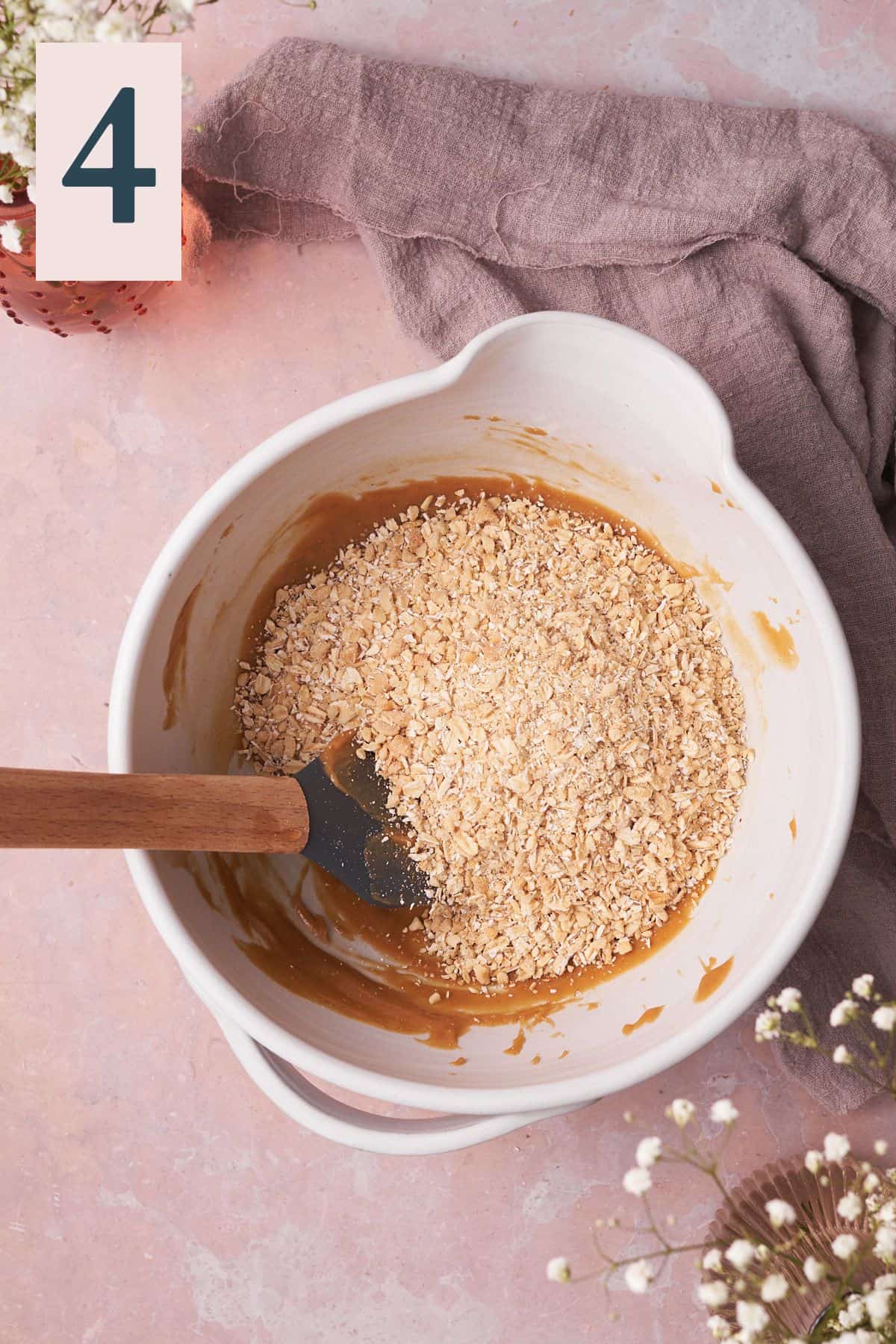pulsed oat mixture in a mixing bowl with melted peanut butter.