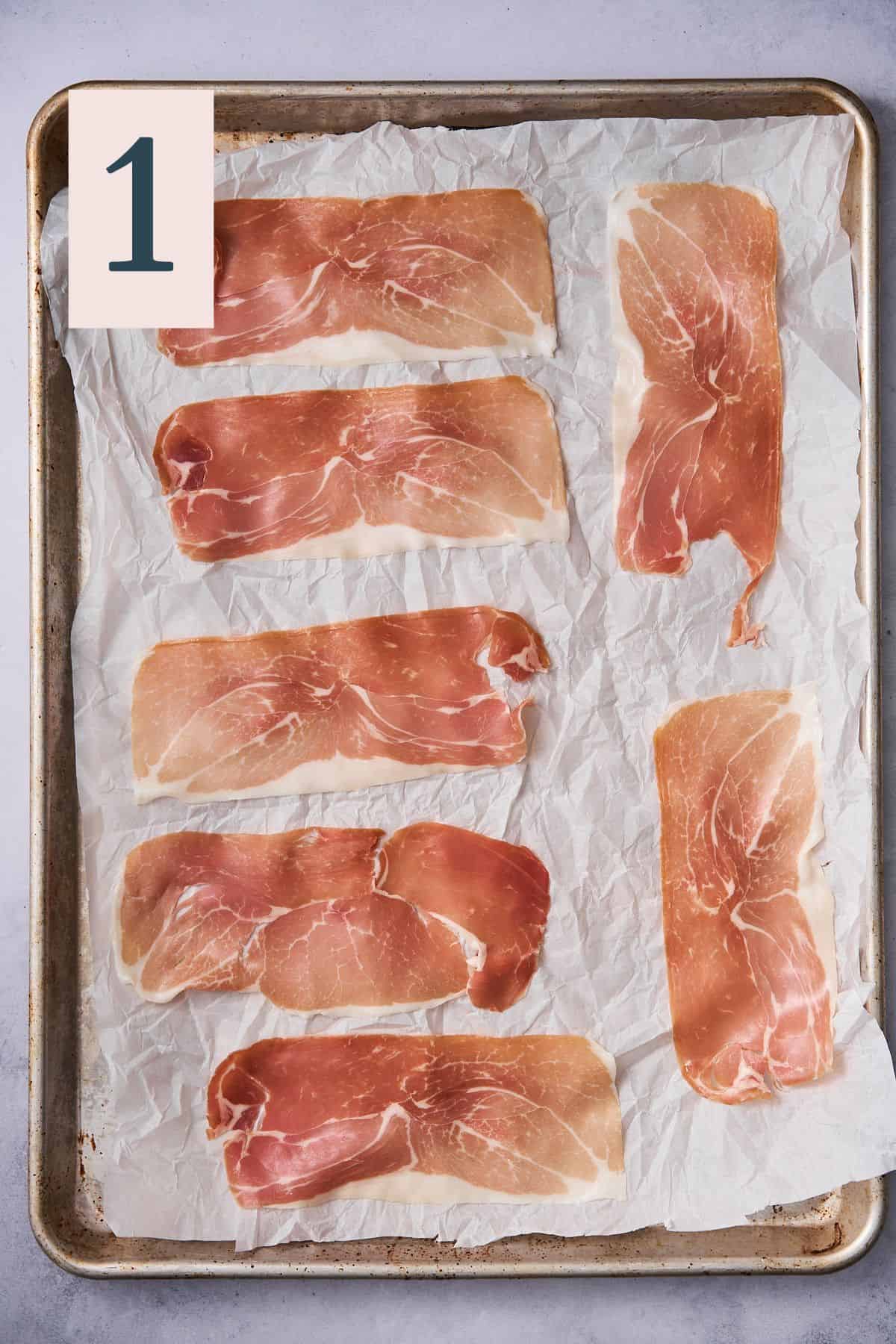 raw prosciutto on a parchment lined baking sheet.