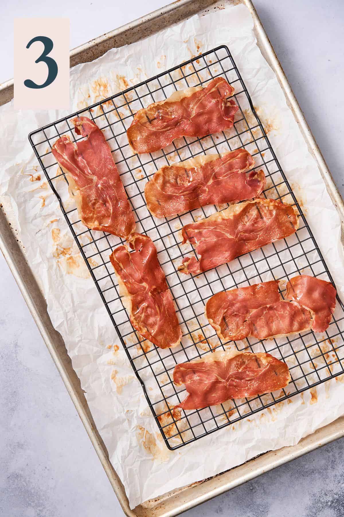 prosciutto cooling on a black wire cooling rack over parchment paper. 