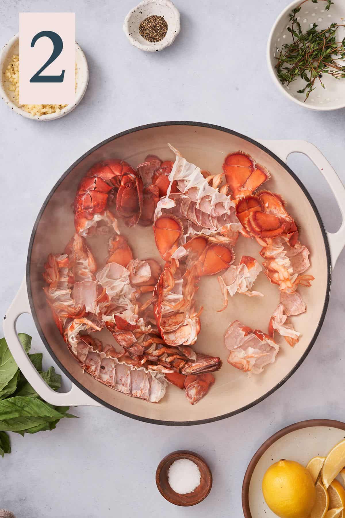 bright red lobster shells in an enameled skillet with white wine in the pan. 