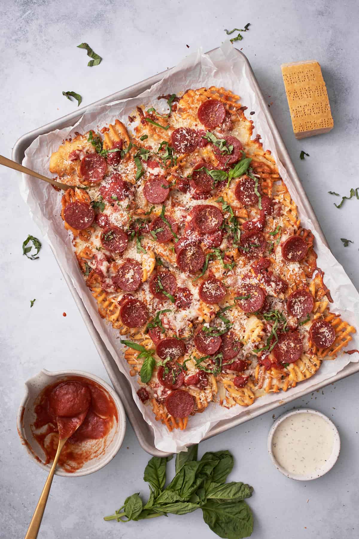 Waffle pizza fries with pepperoni, basil, and cheese on a tray.