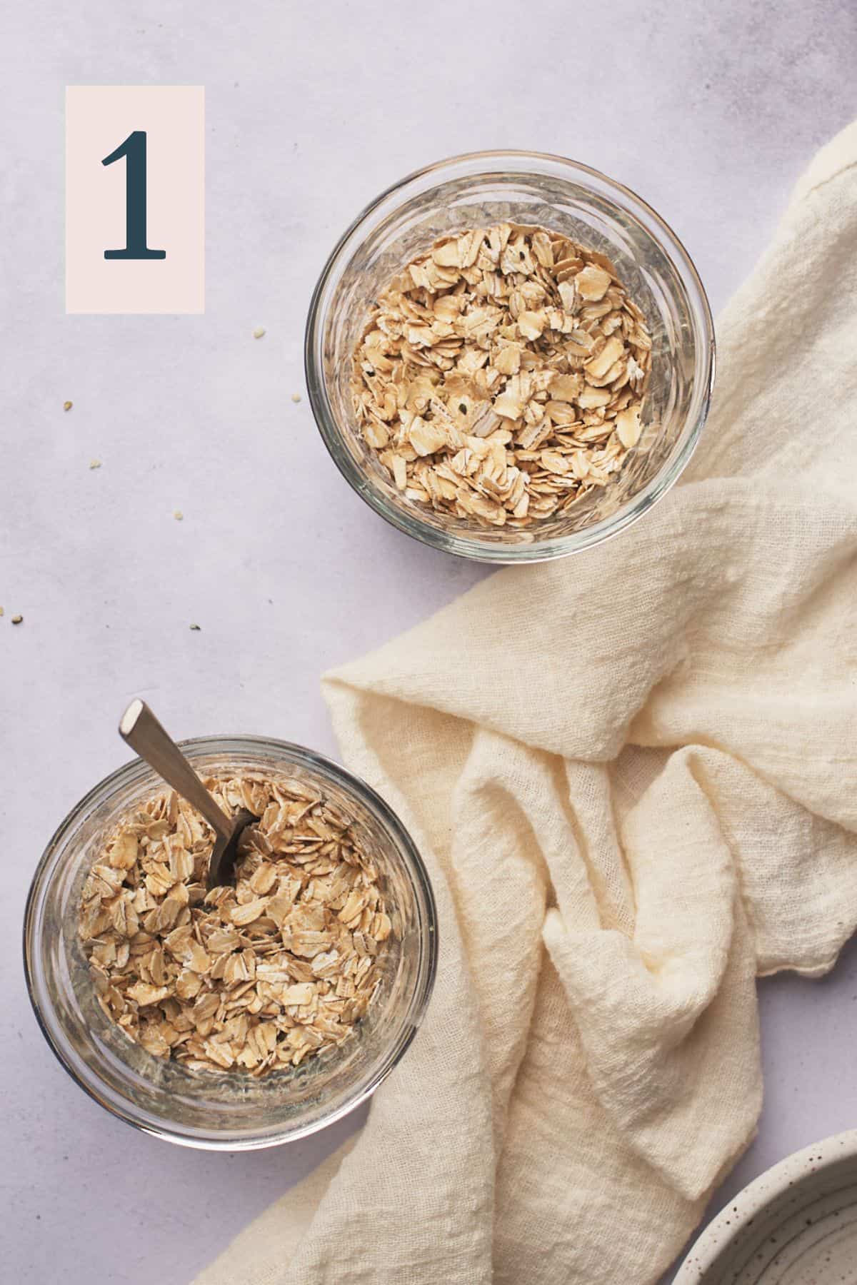 dry oats, chia seeds, hemp hearts, and other dry ingredients in a glass jar, and a spoon inside of one to mix up ingredients. 