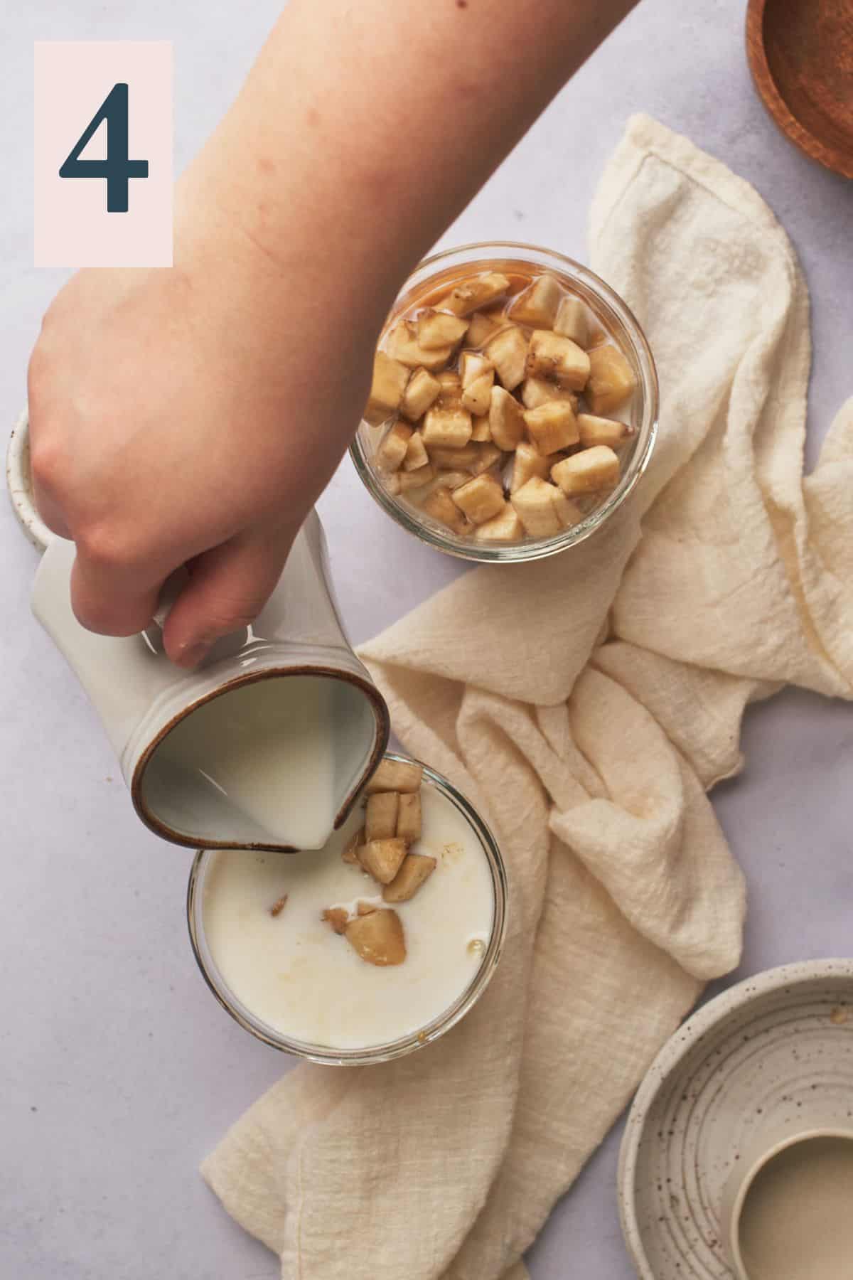 hand pouring in milk to a jar with bananas, oats, and maple syrup.