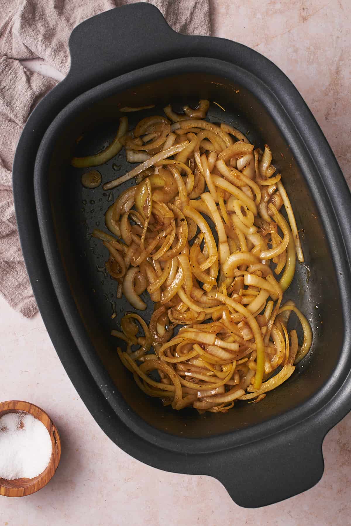 Cooked onions starting to brown in a slow cooker.