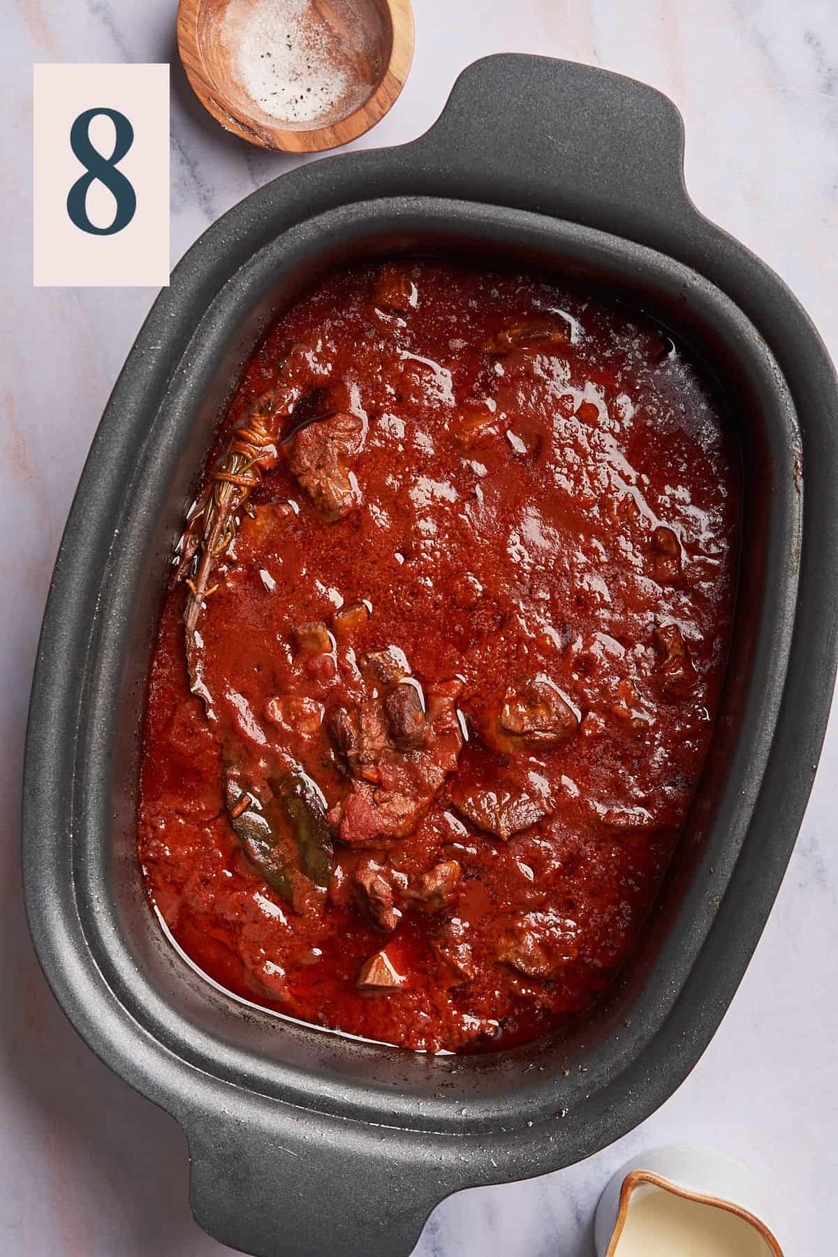 cooked lamb ragu in a slow cooker that has turned a deep red. 