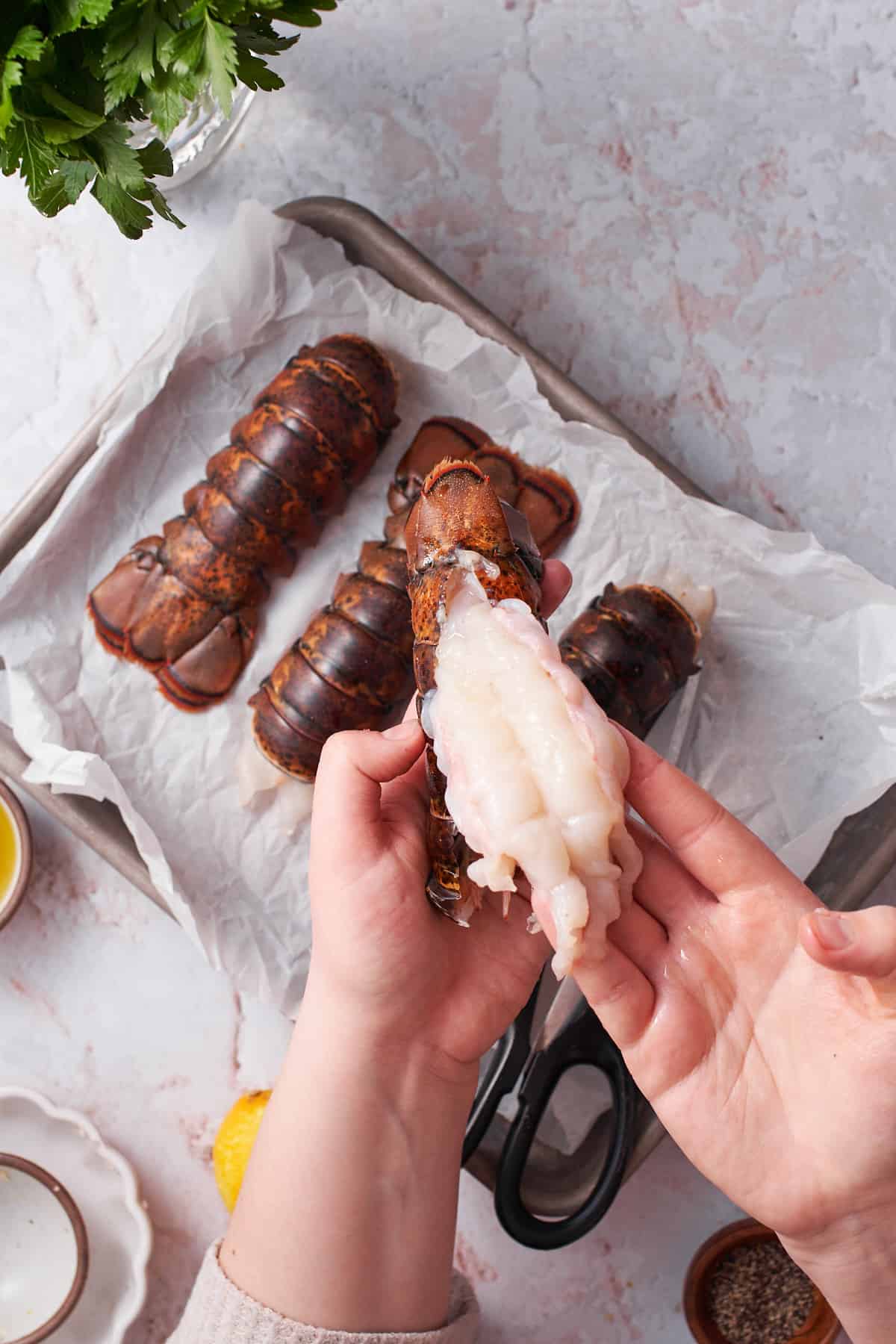 Hand pulling lobster tail meat from a shell.
