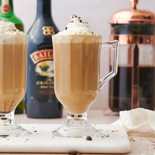 Baileys coffee with jameson whiskey, whipped cream, and fresh brewed coffee in the background.