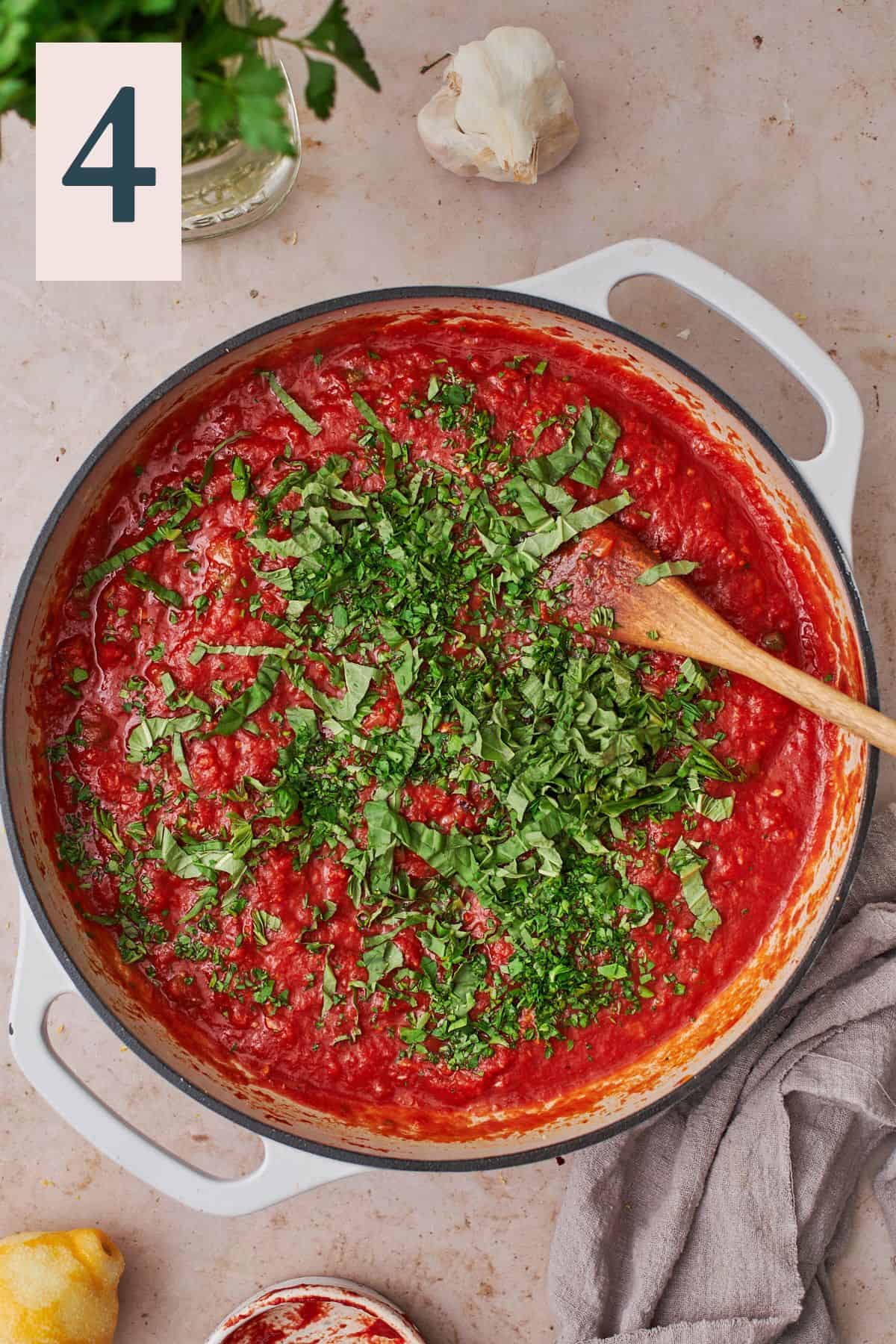 rich tomato sauce in a skillet with lots of fresh basil put into the sauce.