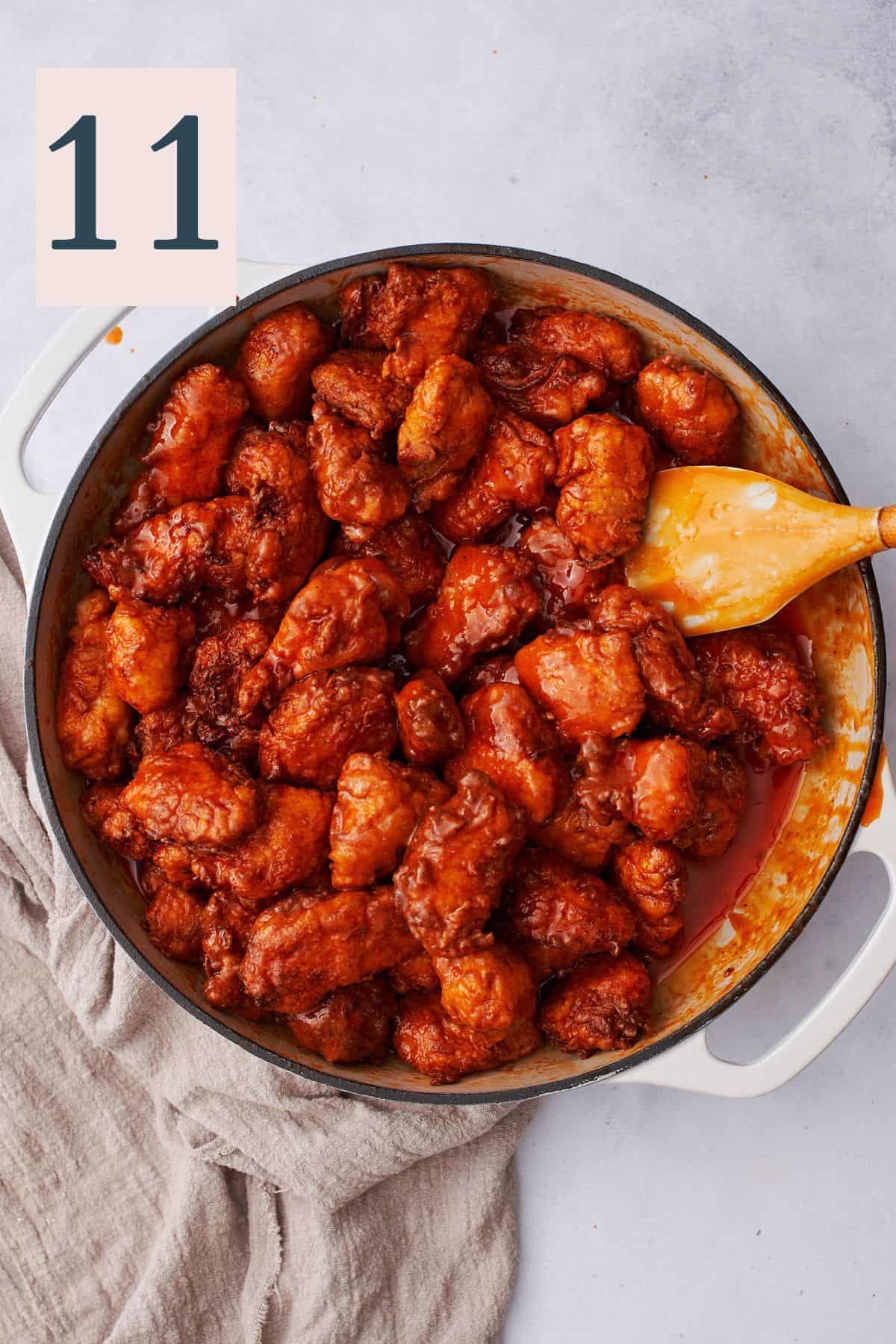chicken pieces coated in a buttery buffalo sauce in a large skillet. 