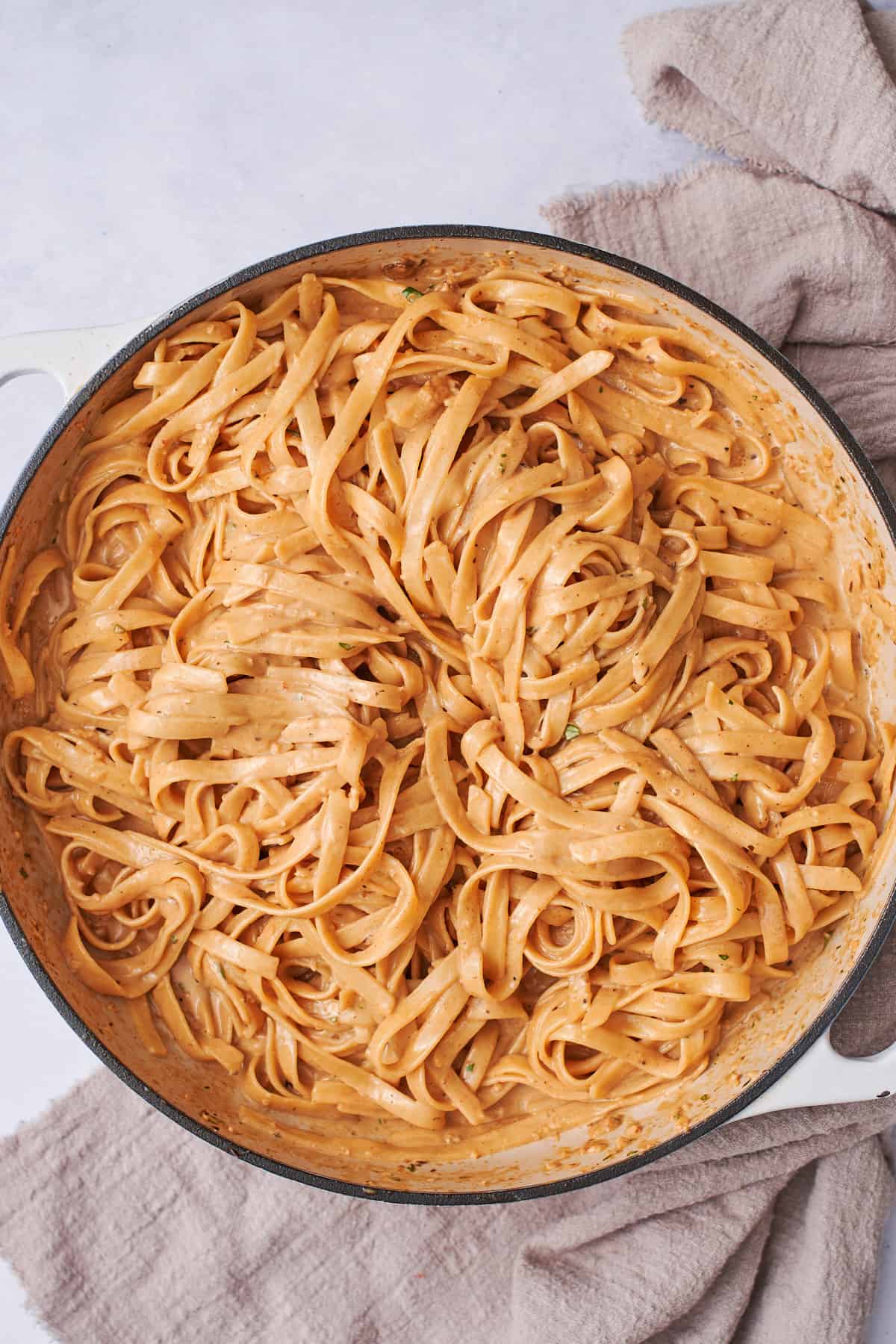 cooked pasta tossed in creamy pasta sauce in a skillet.