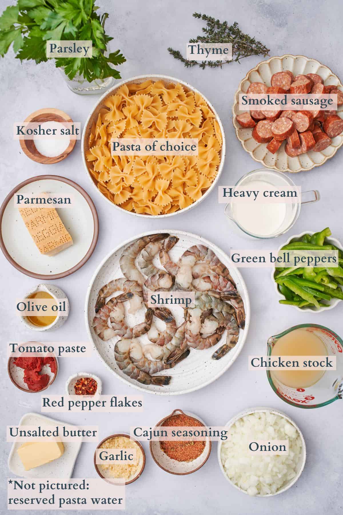 ingredients to make cajun shrimp and sausage pasta laid out on plates and in bowls, labeled to denote each ingredient. 
