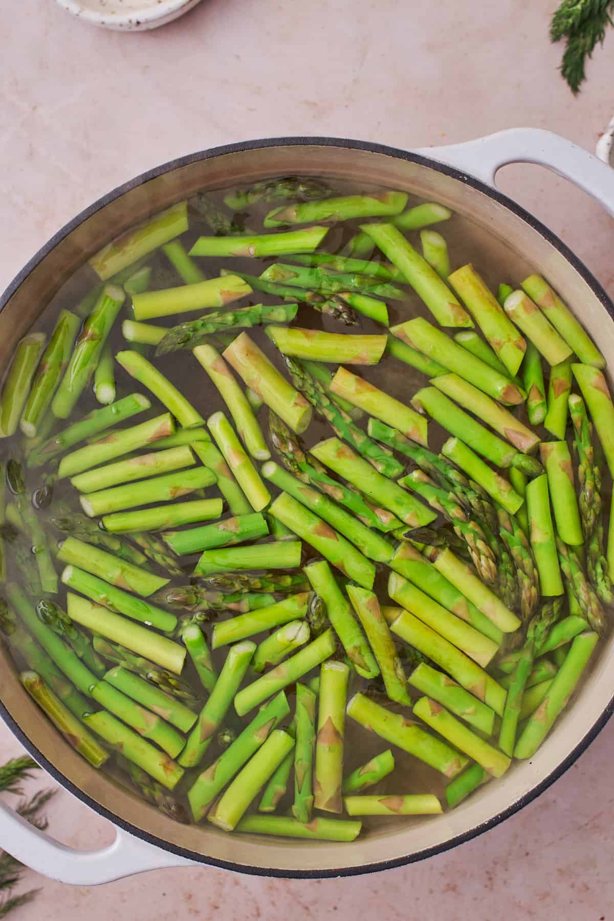 Boiling small asparagus pieces in a large pot.