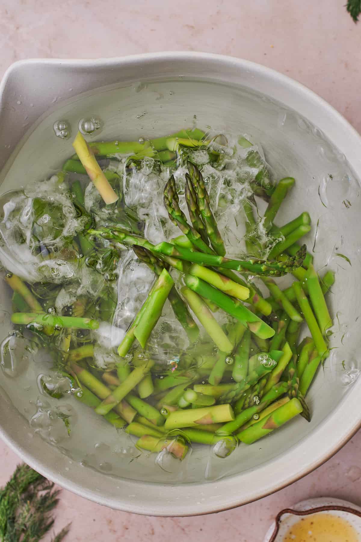 Plunging cooked asparagus into an ice bath to blanch them.