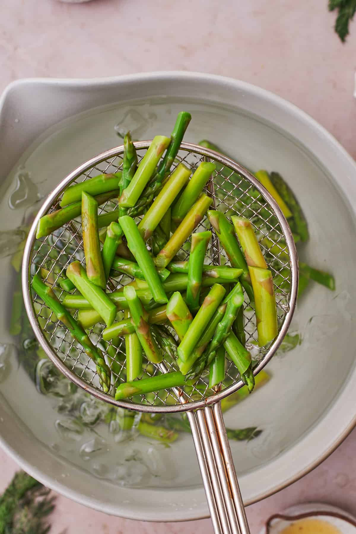 Removing asparagus from cold ice water with a strainer.