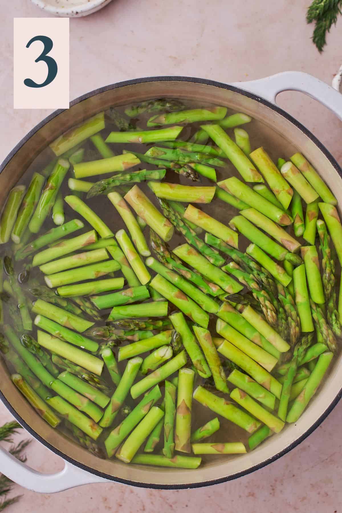 Boiling small asparagus pieces in a large pot.