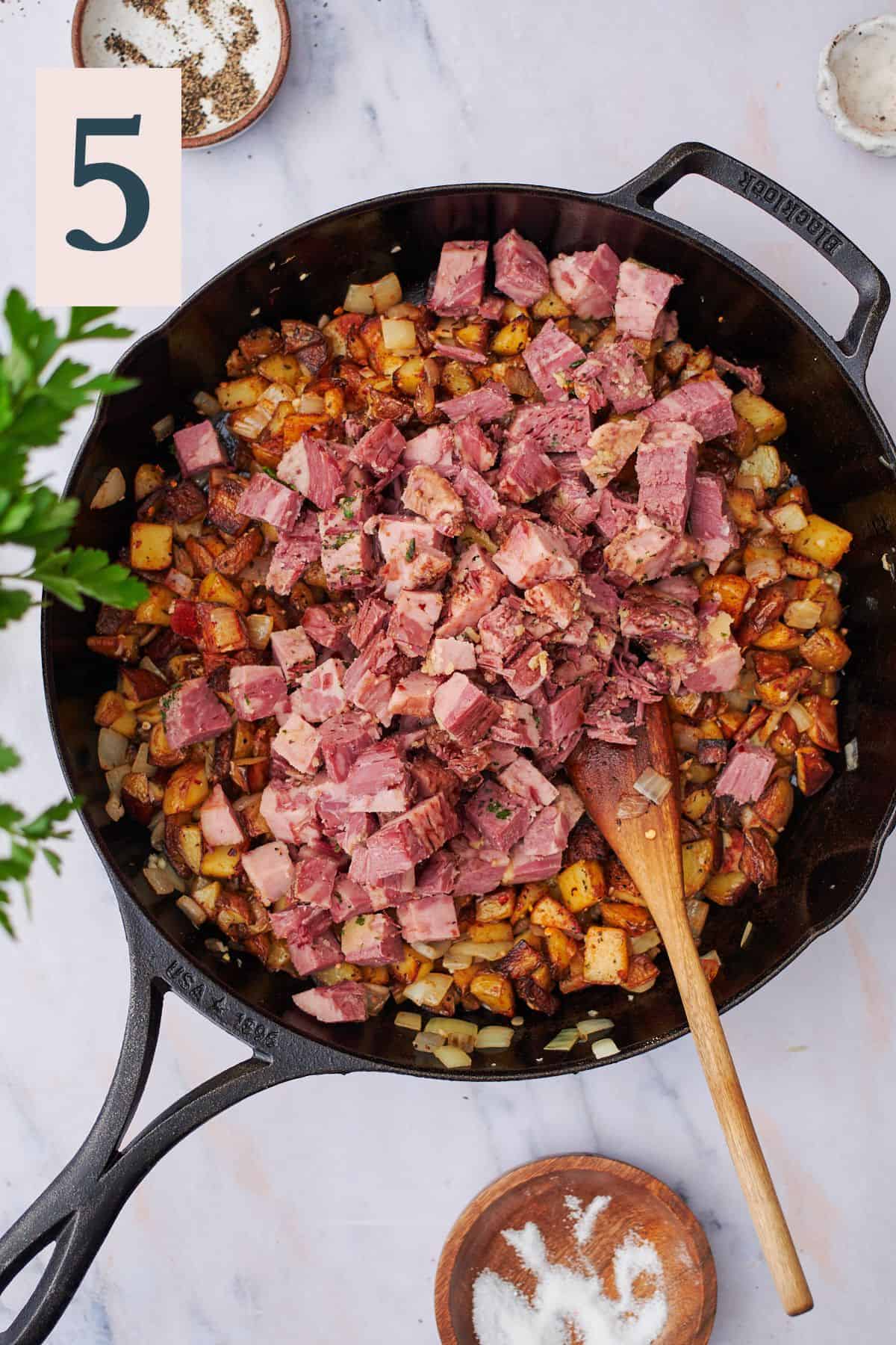 corned beef in a skillet with potatoes and onions.