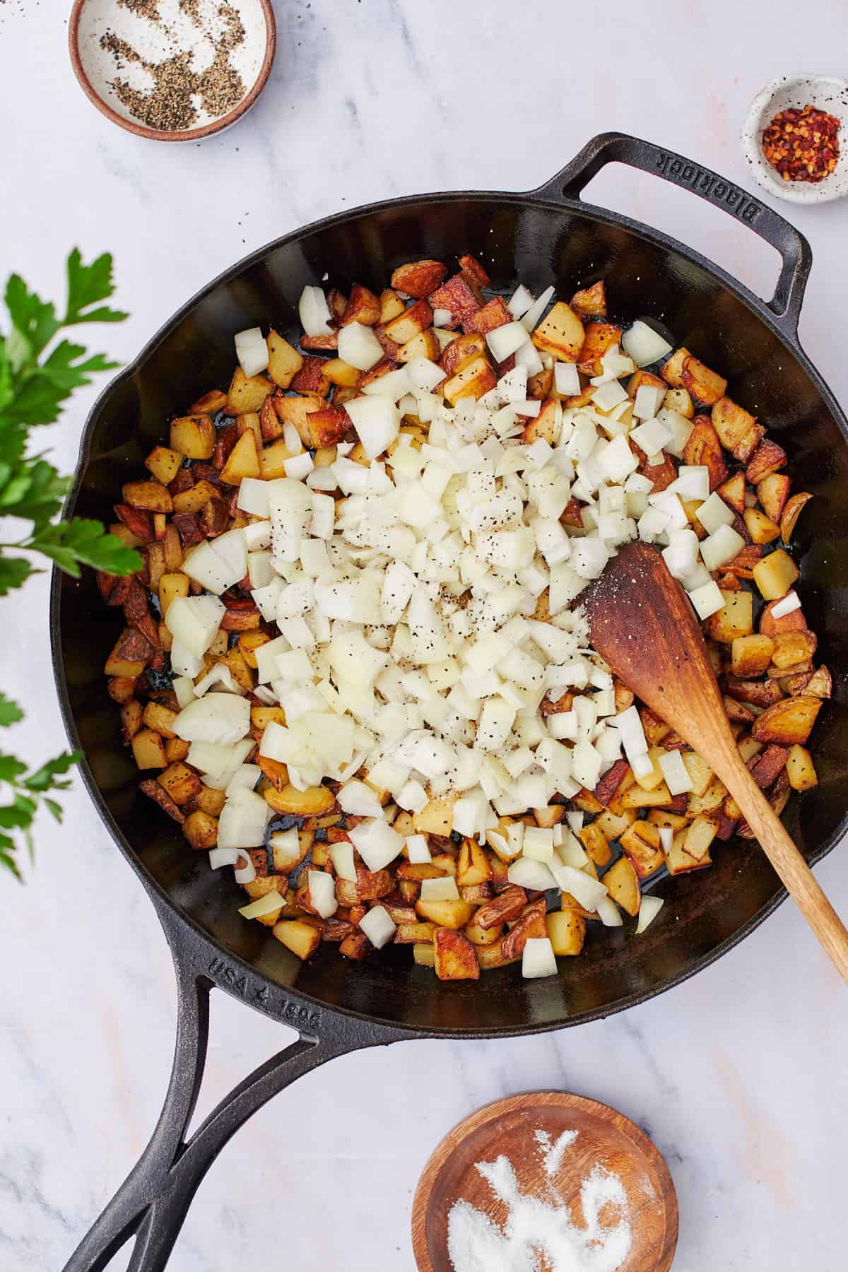 raw onions in a skillet with crispy potatoes.