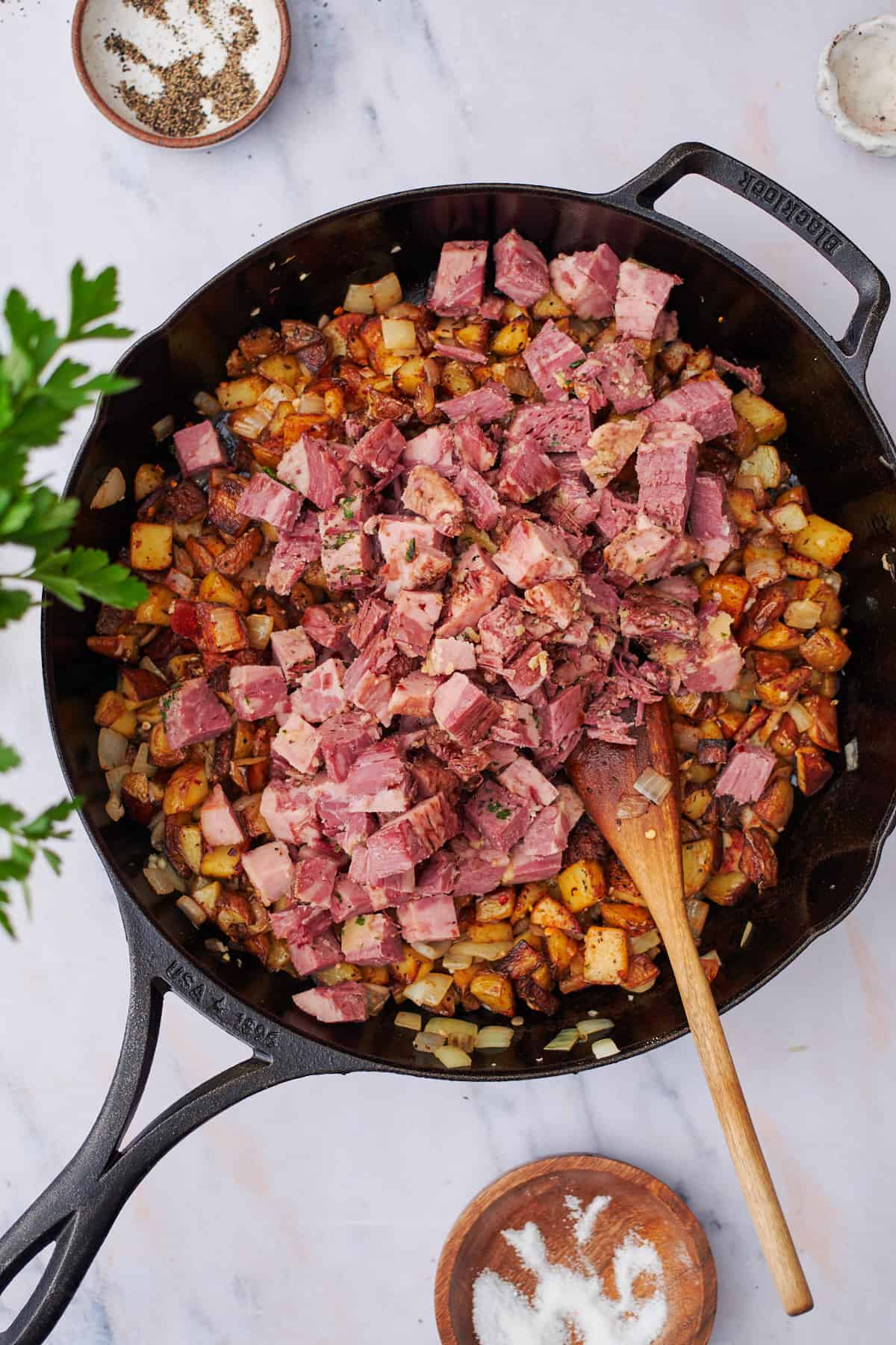 corned beef in a skillet with potatoes and onions.