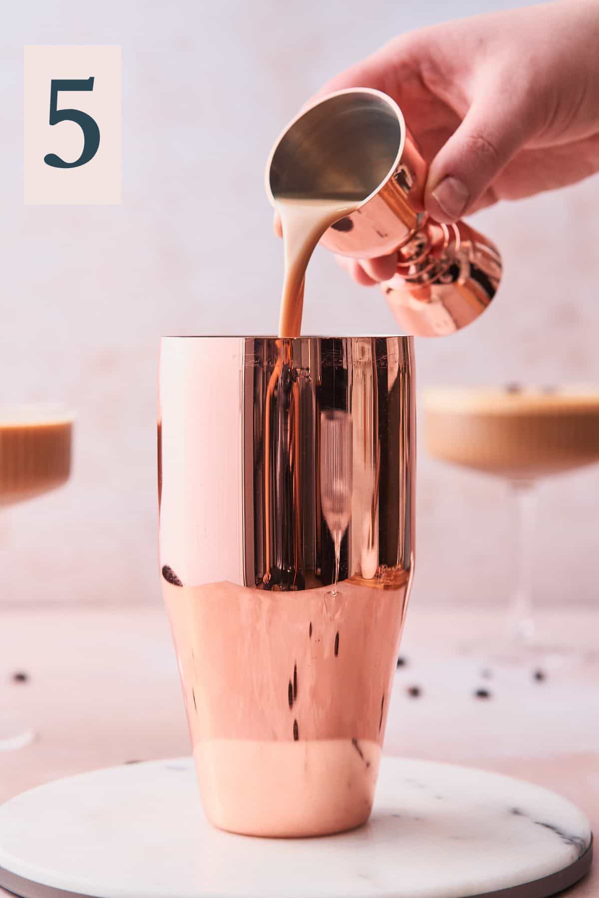 hand pouring Baileys into a cocktail shaker surrounded by espresso martinis. 