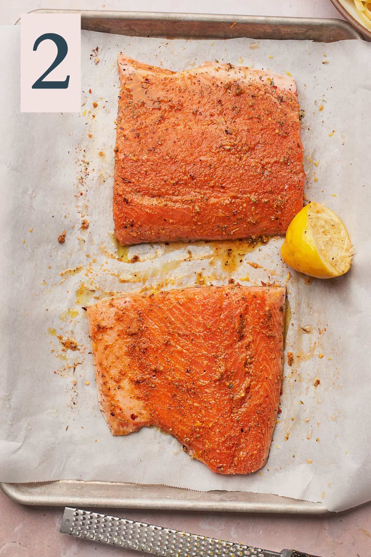 raw salmon seasoned with seasonings and lemon on a baking sheet