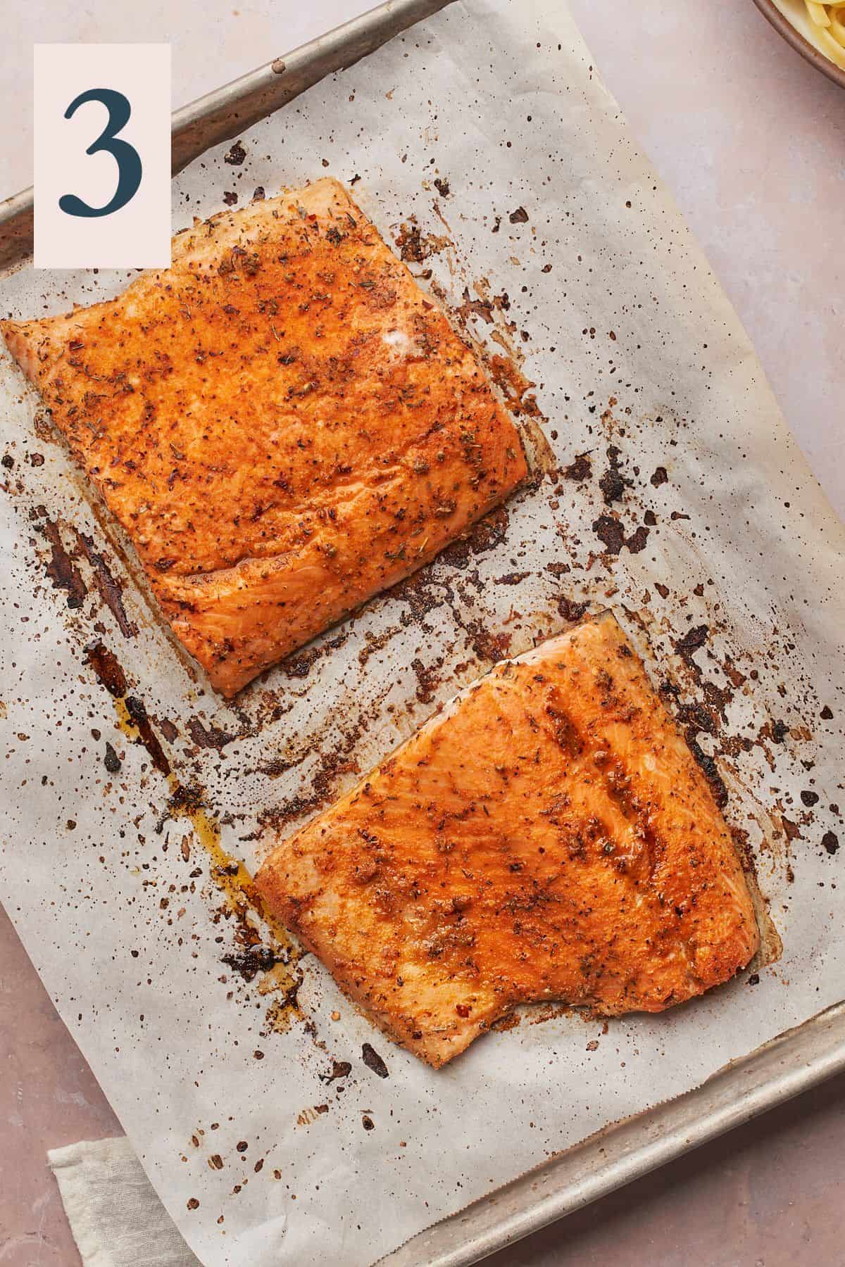 well seasoned and cooked salmon on a parchment lined baking sheet. 