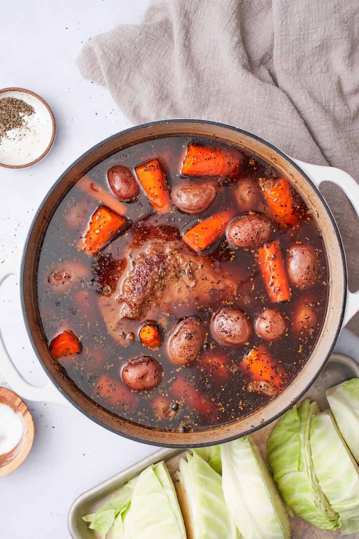 cooked corned beef brisket with carrots and potatoes in the pot.