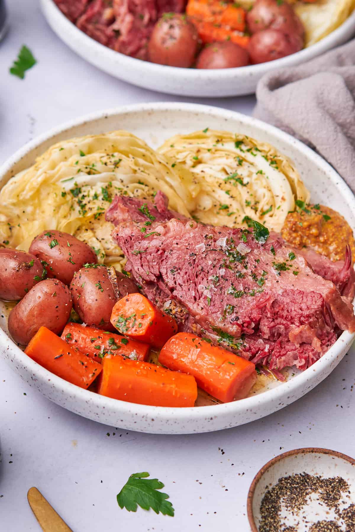 dutch oven corned beef and cabbage with potatoes and carrots on a white speckled ceramic plate. 