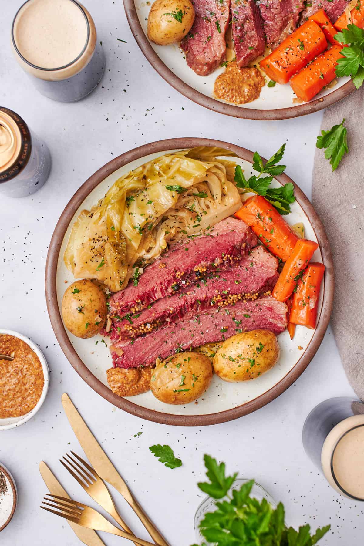 corned beef and cabbage on a plate with yellow potatoes, carrots, parsley, and stone ground mustard, with guinness on the table.