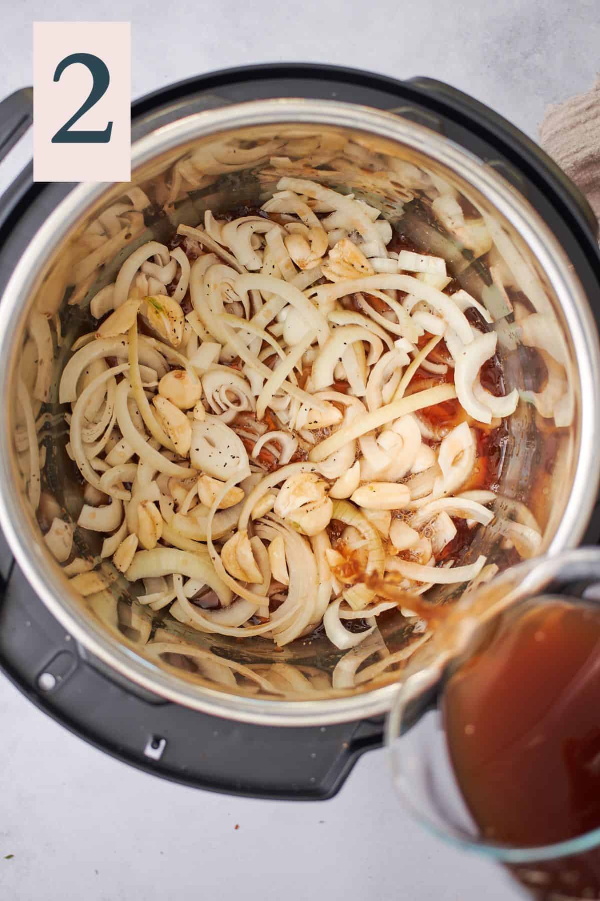 pouring beef stock into an instant pot with garlic and onions that have been seasoned with salt and pepper.